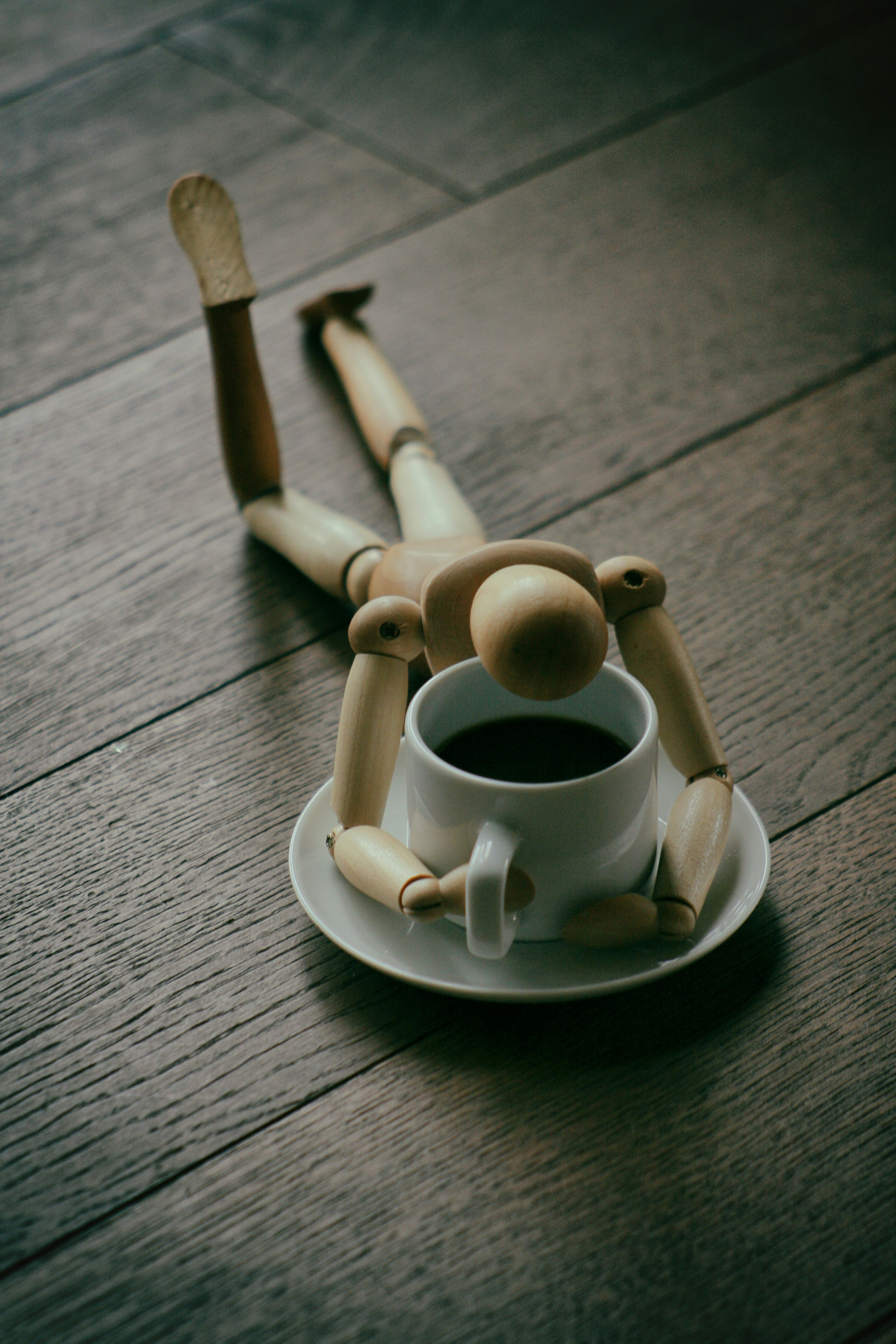 A wooden figure collapsed beside a coffee cup, capturing the exhaustion that comes with chronic poor sleep
